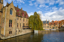 The Rozenhoedkaai Canal In Bruges With A View Of A Large Weeping Willow Tree 