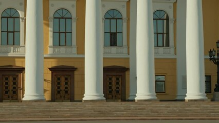 Wall Mural - No people establishing shot of part of 20th century classic style theatre exterior with white columns, wooden doors, arched windows and yellow wallsNo people establishing shot of part of 20th century 