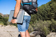© ADDICTIVE STOCK - Anonymous man with laptop and backpack on cliff