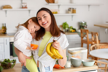 little girl with her mother and healthy fruits in kitchen