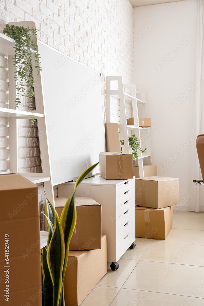 Chest of drawers with cardboard boxes in office on moving day