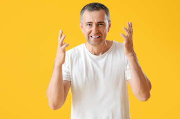 Canvas Print - Portrait of angry mature man on orange background