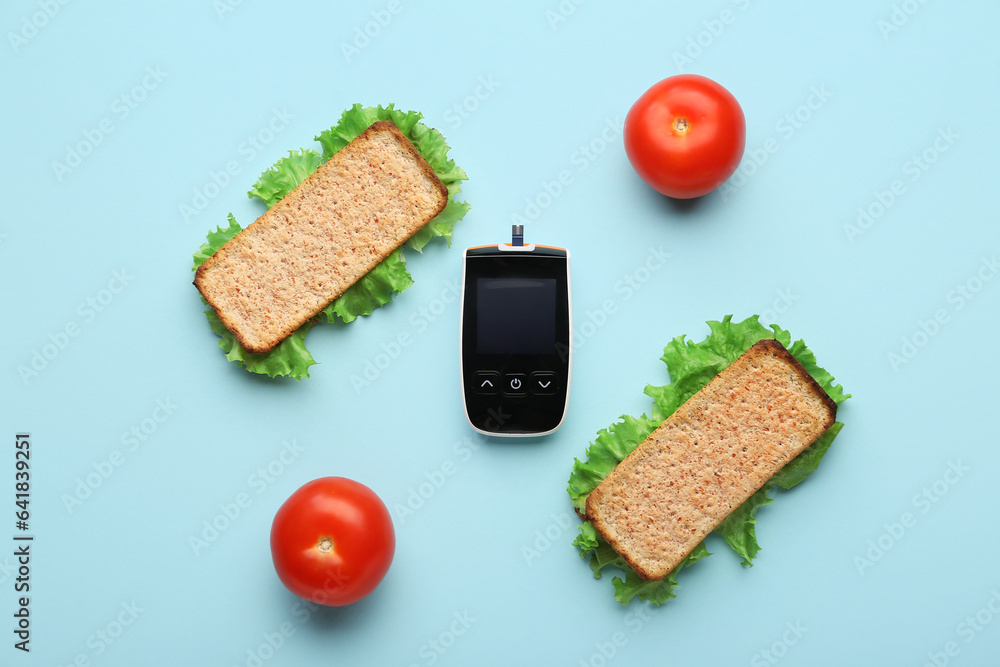 Glucose meter with tomatoes and healthy sandwiches on blue background. Diabetes concept