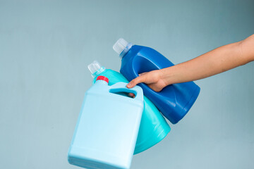 Wall Mural - Hand holding some blue liquid soap bottles on blue background