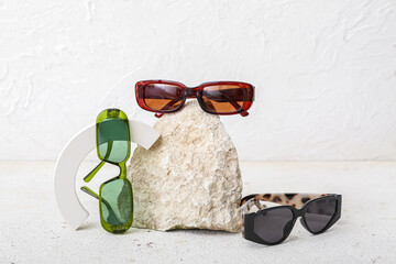 Decorative podium and stone with stylish sunglasses on white background