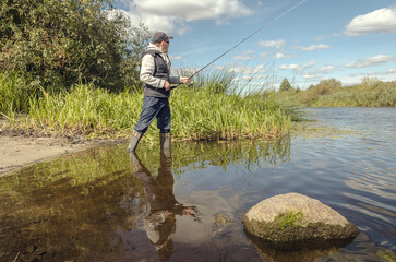 Wall Mural - Man catching fish, pulling rod while fishing.