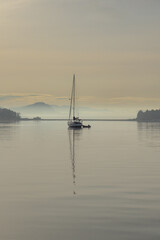 Wall Mural - Sailboat at anchor in Lopez Island's Hunter Bay on a morning with wisps of fog in the distance creates a peaceful scene.