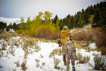 Father and son archery hunting for deer in the Montana snow