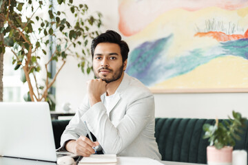 Indian confident young man in formal suit, entrepreneur, sales manager working on laptop