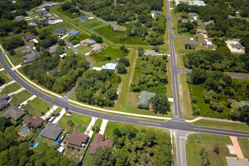 Wall Mural - Aerial view of street traffic with driving cars in small town. American suburban landscape with private homes between green palm trees in Florida quiet residential area