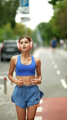 Wall Mural - The city setting witnesses a girl in sportswear and headphones going on her morning run.