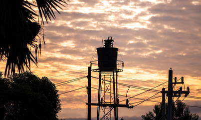 Wall Mural - Silhouette of a water tower in the evening at sunset.
