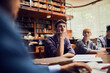 © Marko Geber - Young and diverse group of students studying in a university library with the help of their professor