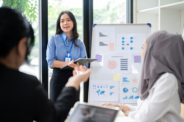 Wall Mural - A confident Asian businesswoman is answering a question from her team during her presentation