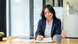 © bongkarn - An attractive Asian businesswoman is signing documents, or taking notes on paper at her desk