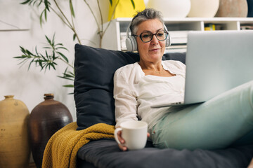 Senior woman is using her laptop to watch a movie on the internet.