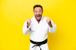 Middle age caucasian man doing karate isolated on yellow background celebrating a victory in winner position
