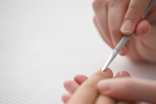 Close Up Of Manicurist's Hand Pushing Woman's Cuticles With Cuticle Pusher

