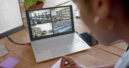 Poster - African american female security officer watching school cctv camera views on laptop, slow motion