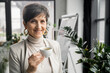 © LIGHTFIELD STUDIOS - joyful middle aged businesswoman with coffee cup looking at camera in office, professional headshot