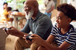 © Monkey Business - Grandfather And Grandson Sitting On Sofa At Home Playing Video Game Together