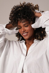 Young woman with afro hairstyle smiling. Girl wearing white shirt. Studio shot.