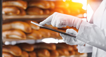 Baker Use Tablet Computer For Control Quality Of Craft Bread In Bakery Factory, Sun Light. Modern Food Industry Banner