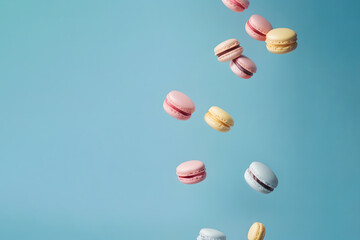 Colorful French macarons falling on the pastel blue background. Creative sweet food design concept.