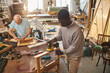 © Seventyfour - Portrait of young black man building wooden furniture while working in carpentry workshop and using electric tools, copy space