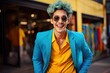 © Eva Corbella - Smiling Asian man with blue hair, yellow shirt and blue jacket, is smiling in the city.