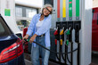 © Ivan Traimak - a mature woman with gray hair stands at a gas station and refuels the car for a trip and speaks on the phone