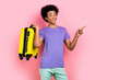 Portrait of funky guy with perming coiffure wear stylish t-shirt hold valise indicating empty space isolated on pink color background
