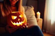Woman Sitting With Illuminated Pumpkin For Halloween.