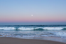 Full Moon Rising In Dusk Light Over Ocean And Sandy Seashore 