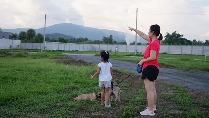 Wall Mural - Side view of mother and daughter with dogs standing at field.