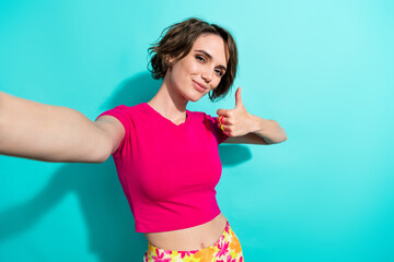 Photo of cheerful lovely girl make selfie hand finger demonstrate thumb up isolated on teal color background