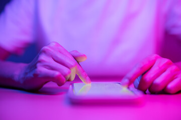Wall Mural - Woman use mobile phone on the table under pink light