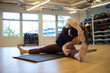 © Mat Hayward - Physically fit woman stretching before exercise in a gym. She is exercising on a yoga mat.