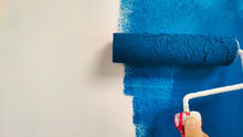 Roller With Blue Paint On A White Wall