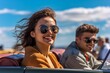 © vachom - Happy young couple driving in convertible car on road trip. Man and woman laughing and having fun together. Beautiful young woman  with flying hair in the air.