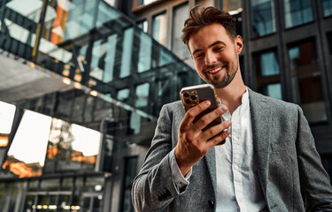 portrait of attractive confident modern smiling happy adult dressed gray suit man holding a phone an