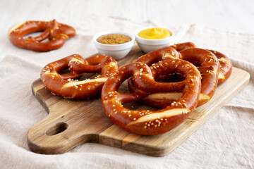 Wall Mural - Homemade Soft Bavarian Pretzels with Mustard on a wooden board, side view.
