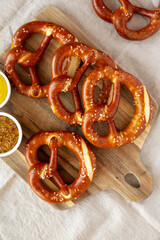 Wall Mural - Homemade Soft Bavarian Pretzels with Mustard on a wooden board, top view.