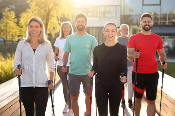 Canvas Print - Group of people practicing Nordic walking with poles outdoors on sunny day