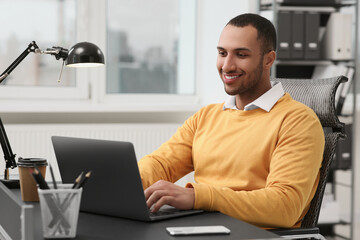 Canvas Print - Young man working on laptop at table in office