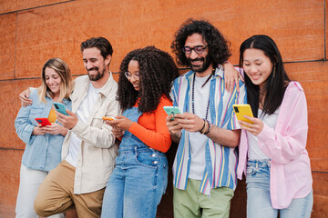 Group of friends having fun using a cellphone to browse on internet. Young adult people sharing photos with smartphone social media application. Buddies smiling and laughing watching the mobile phone