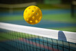 © G.Edwards - Yellow Pickleball crossing a Pickleball net with shadow on the top tape.