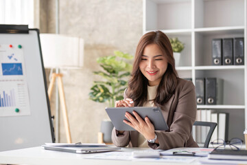 Wall Mural - Cheerful business lady working on laptop in office, Asian happy beautiful businesswoman in formal suit work in workplace. Attractive female employee office worker smile.