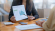 © amnaj - Businesswoman pointing at financial data graph in office meeting