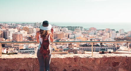 Wall Mural - Woman with hat looking at panoramic view of Spanish urban skyline city- Almeria in Spain